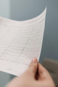 A detailed view of a person holding an electrocardiogram printout in a soft focus setting.