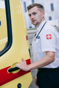 Professional male paramedic in uniform standing by ambulance door outdoors, ready for action.